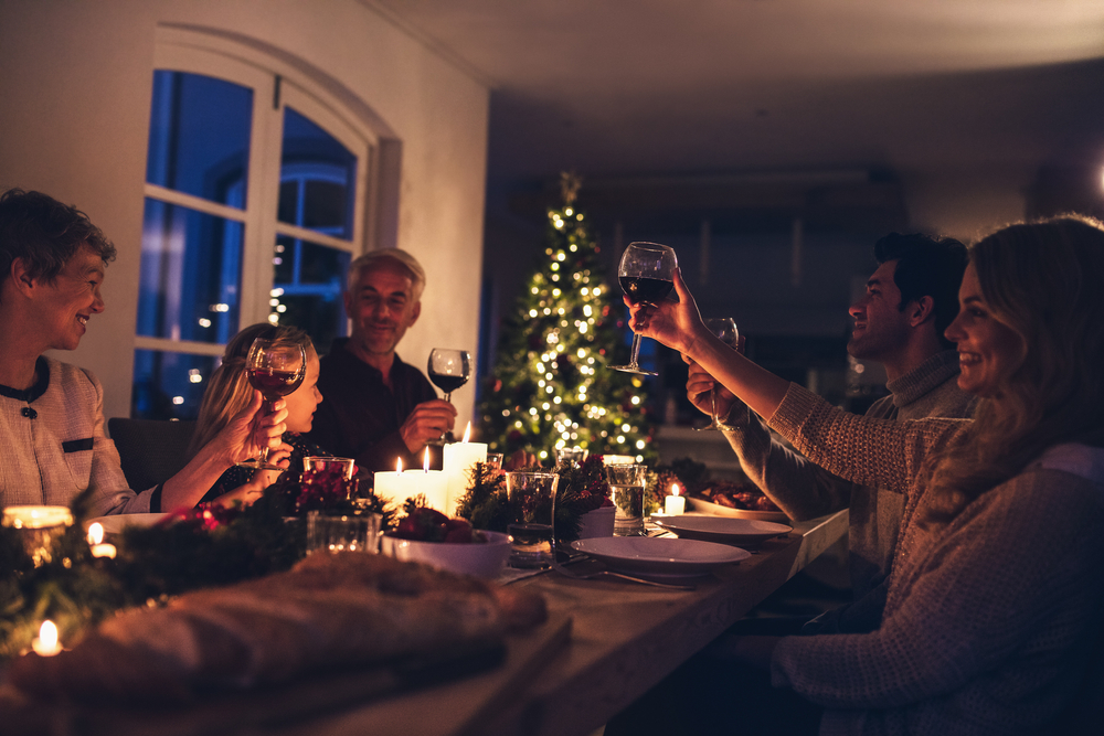 ロウソクの明かりが灯る自宅でワイン片手に家族とディナーを楽しんでいる