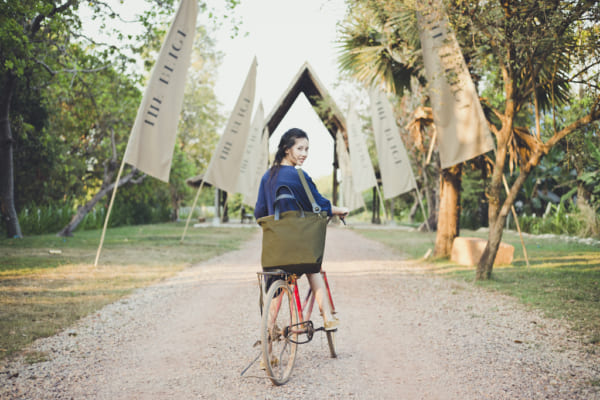 自転車に乗った女性が旅行バッグを持っている