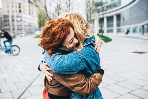 Two friends redhead and blonde girl meeting in the street of the city and hugging Ã¢??friendship, happiness concept