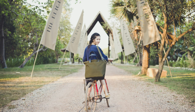 自転車に乗った女性が旅行バッグを持っている