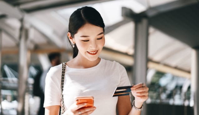 Business people shopping via online application media concept. Happy smile young adult asian woman consumer using creadit card and smartphone. City on day background with copy space. Processed with VSCO with j2 preset