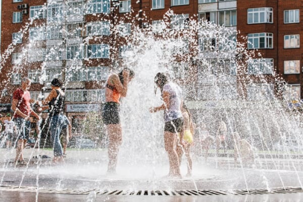 Novokuznetsk, Kemerovo Region, Russia - August 04, 2018: Happy children splashing in a water of a city fountain and enjoying the cool streams of water in a hot day. Hot summer.
