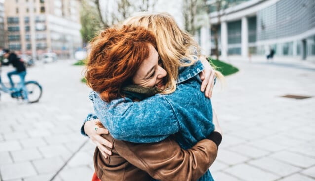 Two friends redhead and blonde girl meeting in the street of the city and hugging Ã¢??friendship, happiness concept