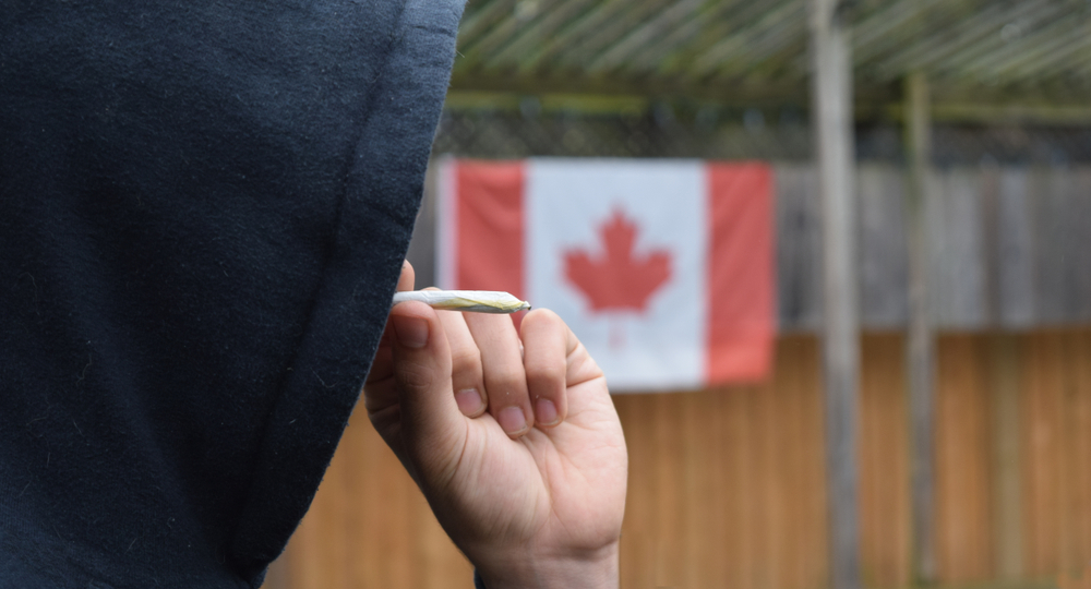 カナダ国旗を背景に喫煙する人