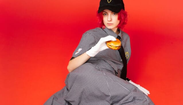 ストリートファッションを身にまとい、ハンバーガーを持つ女性
