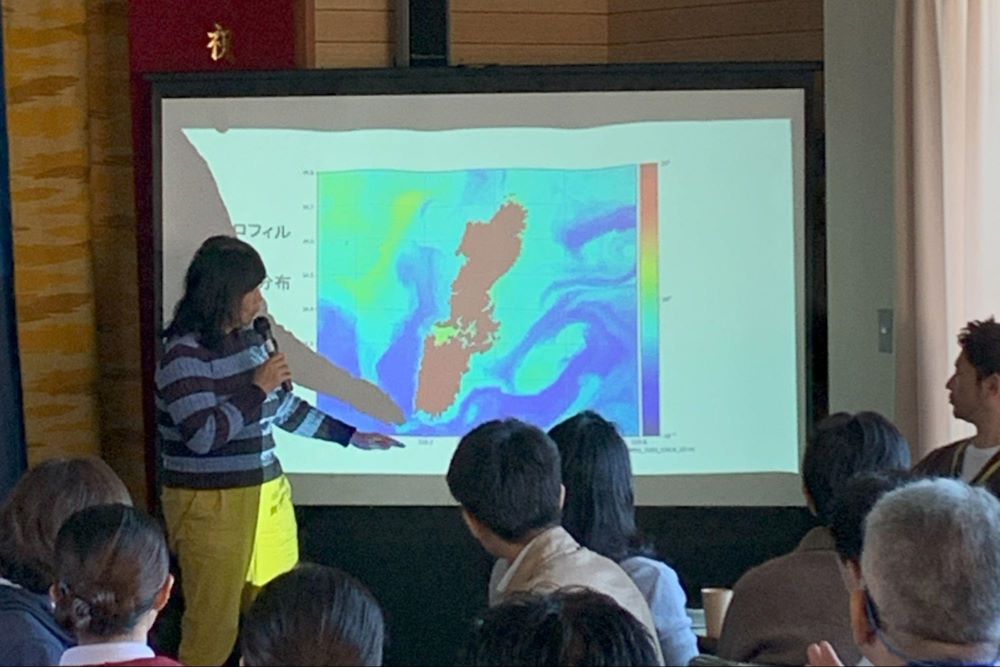講演をする清野聡子准教授と、対馬周辺海域のクロロフィル（栄養分）のマップ。島の東側で渦を巻いていることが分かる