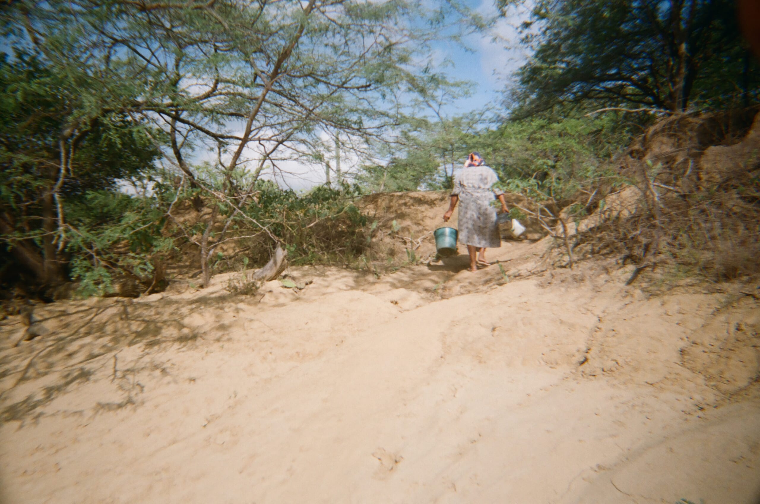 Luz 14- takes a picture of her mother Cenaida 50, walking up a dried riverbank on her way to get water