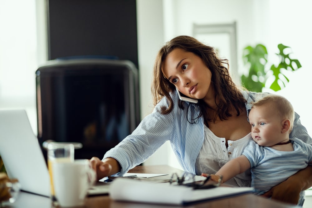 子どもを抱えながら仕事をする女性