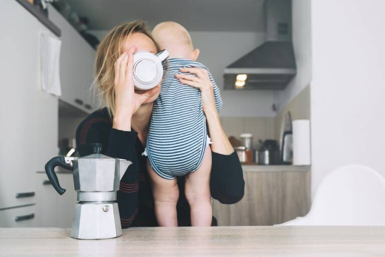 赤ちゃんを抱えながらコーヒーをかっこむ母