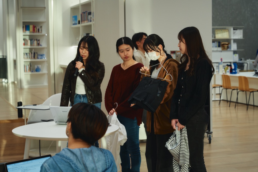 自らリメイクした服をサンプルとして見せながら、プレゼンテーションをする学生チーム。